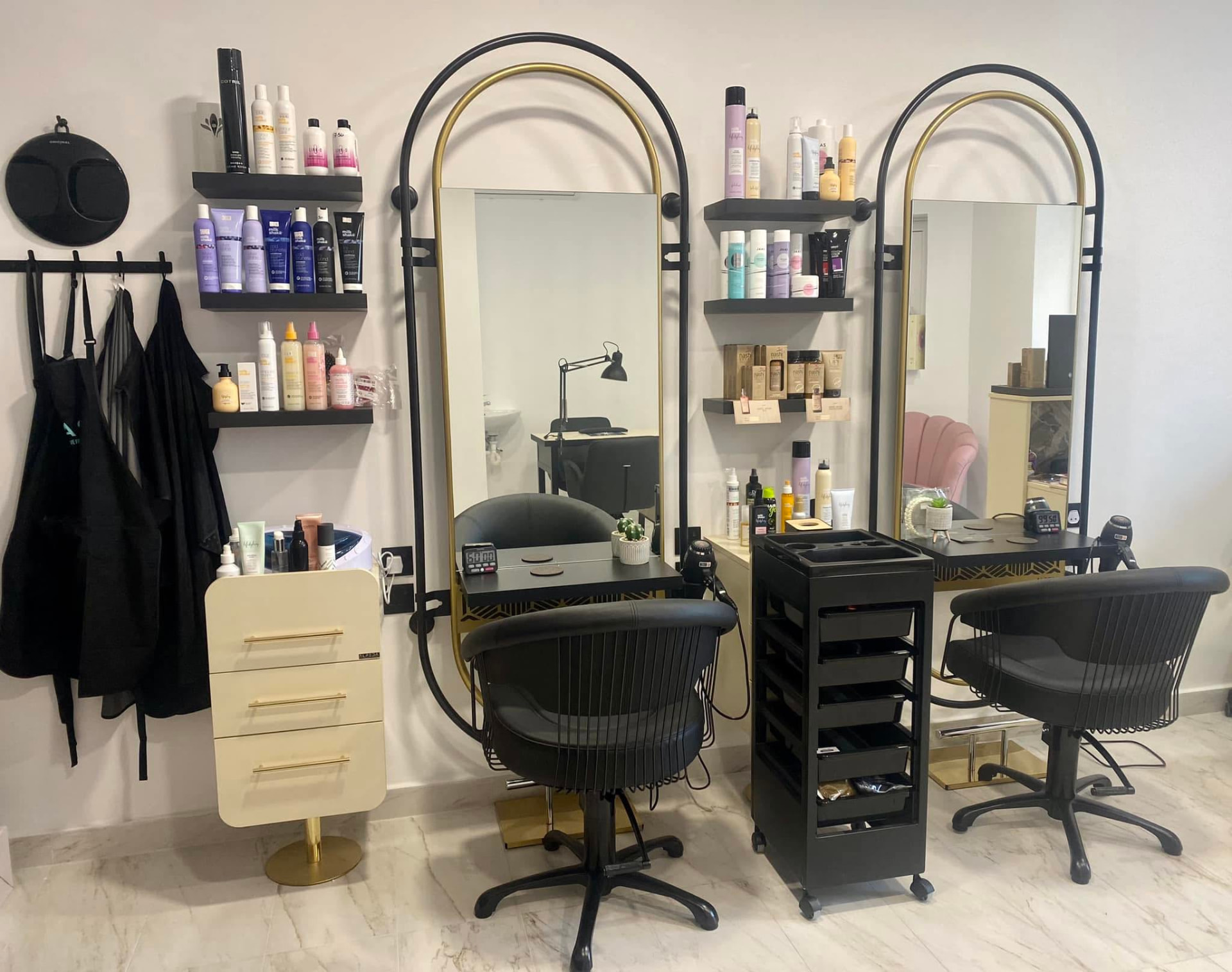 Interior of LV Hair and Nails salon with gold arched mirrors and styling chairs